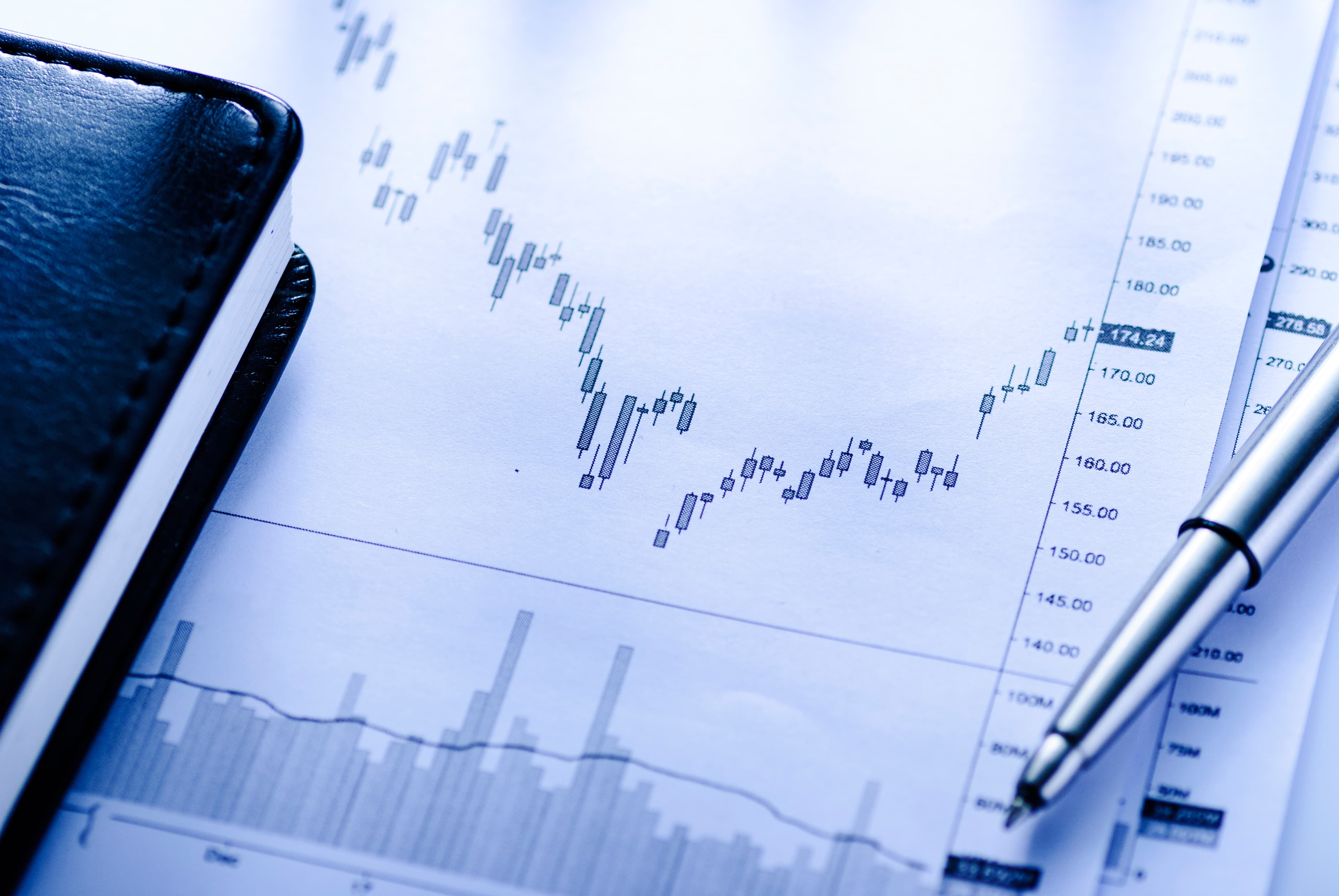 Open business journal with charts and a pen on a desk